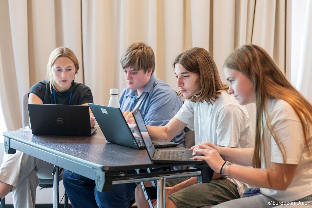 Four young people working on laptop computers.
