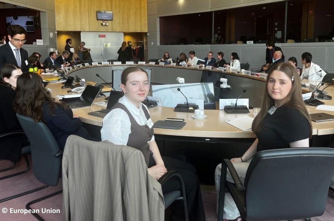 Ayata and Zuzanna sitting at big discussion panel at the European Commission.